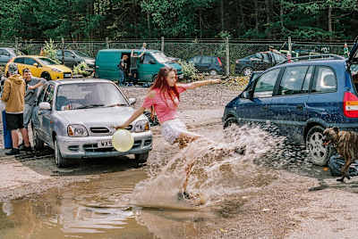 Woman kicking a puddle at a free party in a Quarry, Wales, 2017