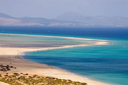 Kitesurfers and windsurfers enjoy the winds off Sotavento Beach on Fuerteventure in Spain