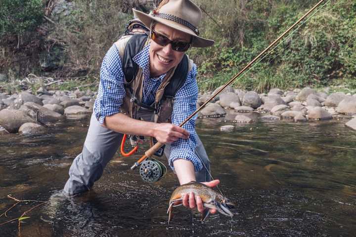 Una persona muestra una trucha de un arroyo en Australia.