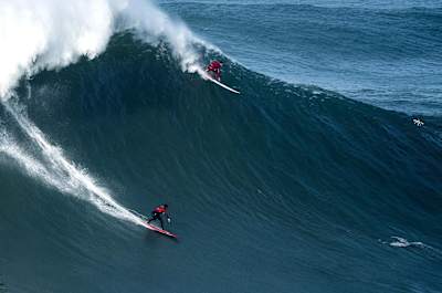 Dois surfers a descerem um incrível swell na Nazaré, Portugal, em dezembro de 2016