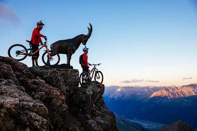 Claudio Caluori and Danny MacAskill stand on top of a mountain taking in the view, Switzerland.