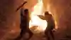 Deacon St John fighting a human by a fire in Days Gone