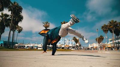 Jeskilz doing some power moves on a palm-lined street.