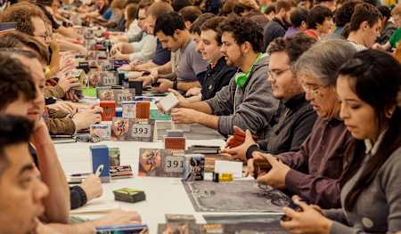 Zahlreiche Spieler sitzen an Tischen und Spielen gegeneinander