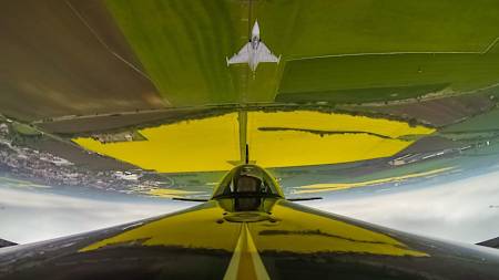 A photo of Red Bull Air Race World Champion Martin Šonka performing barrel rolls in his Extra 300SR aerobatic plane over Czech Airforce display pilot Ivo Kardoš' Gripen jet fighter.