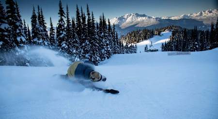 Un snowboardeur carve sur une piste de la station de ski de Whistler Blackcomb au Canada.