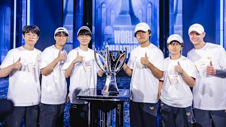 Le roster de l'équipe de T1 pose avec le trophée des Worlds de League of Legends 2024.