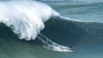 Professional big wave surfers Alex Botelho and Andrew Cotton surf a wave together at Nazaré, Portugal.