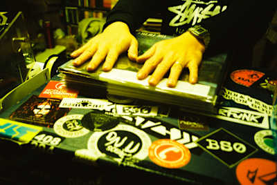 A photo of Disc Shop Zero's Naoki E-JIMA with his hands on a pile of vinyl.