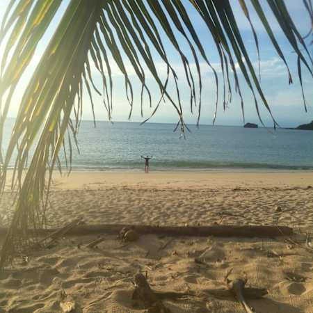 An individual holds up their hands on a beach off the Archipiélago de las Perlas in Panama.