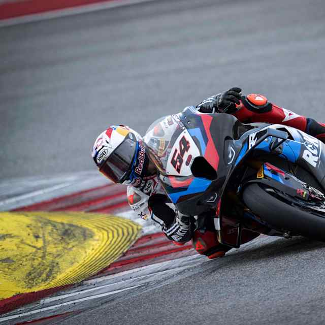 Superbike rider Razgatlıoğlu races around a bend on a track.