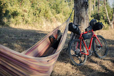 Person in a hammock with bike packed ready for adventure.
