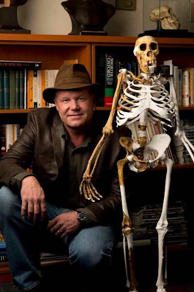 Lee Berger se agacha junto a un esqueleto de sediba en una biblioteca.