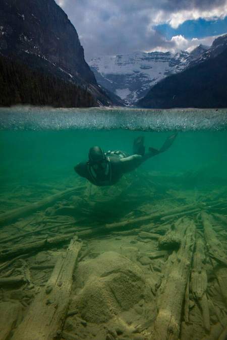 An image of a diver in shallow water with snowy mountains in the background.