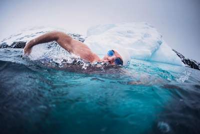Lewis Pugh swims in cold waters near an iceberg.