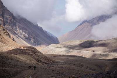 Two people trek across desolate landscape in the Andes.