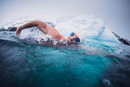 Lewis Pugh swims in cold waters near an iceberg.