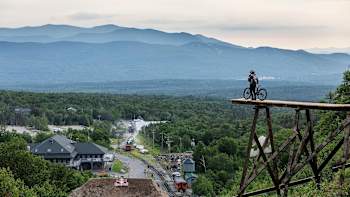 A mountain bike rider watches a train approaching.