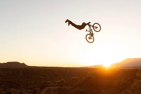 Le Français William Robert plaque une figure en VTT freeride face au lever du soleil dans le désert de l'Utah aux États-Unis.