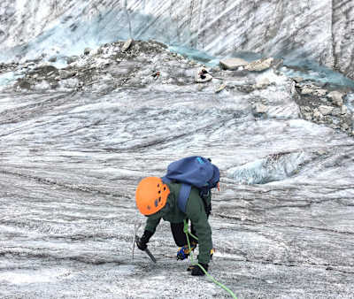 Person uses ice pick to climb up glacier in France.