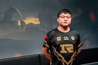 A photo of Jian ‘Uzi’ Zi-Hao in front of LoL artwork.