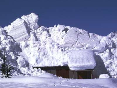 A flowing avalanche deposit that's about to engulf a house.