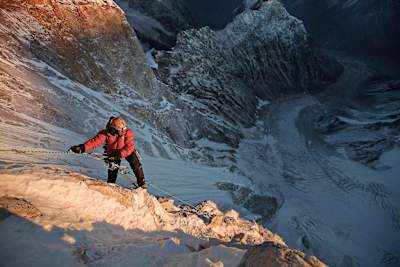 Jimmy Chin holds onto ropes and is basked in sunlight on the summit push of Meru, the Indian Himalayas.