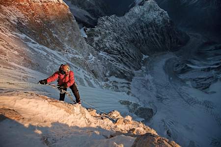 Jimmy Chin holds onto ropes and is basked in sunlight on the summit push of Meru, the Indian Himalayas.