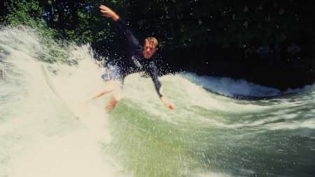 Eisbach-Legende Quirin Rohleder surft die stehende Flusswelle in München in jungem Alter.