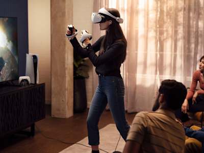Una mujer juega PSVR2 mientras otros miran.