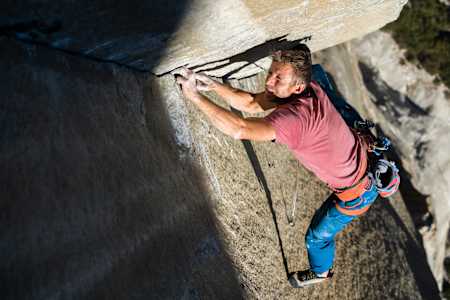 Tommy Caldwell peers up wall in sunlight in Yosemite.