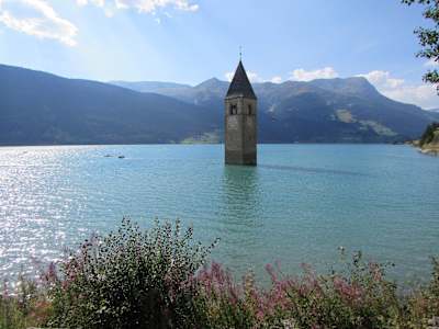 Torre da Igreja, a espreitar para fora das águas azuis do Lago di Resia, nos Alpes italianos.