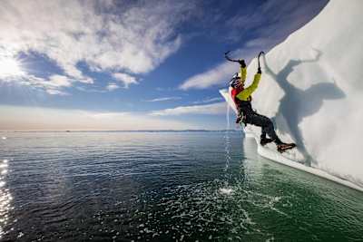 Climber Will Gadd hangs off a ice cap with his picks during his trip to explore the Greenland ice cap in  2018.