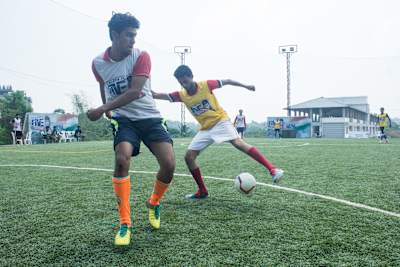 Football players compete for the ball during a match at Sporthood Espirito, Kochi, Kerala.