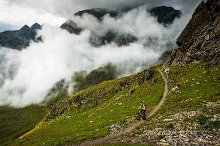 Rider pulls a wheelie on a trail high up in St Moritz.