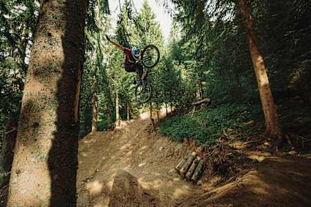 Martin Söderström performs a no-hander trick off a trail jump at Châtel MTB Park.