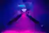 Jesper Tjäder rides the spider rail against a background of blue and pink lighting.
