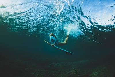 Red Bull surfer Erin Brooks powers under a wave during a dynamic duck dive at the legendary Cloudbreak lineup in Fiji on August 18, 2025, embodying true action sports spirit
