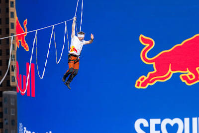 Jaan Roose hanging on a slackline between two buildings in Seoul