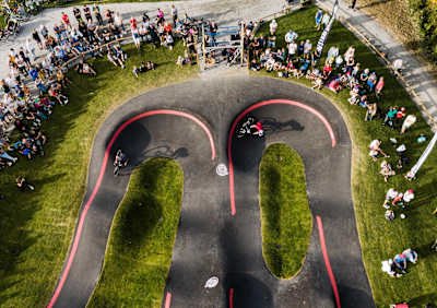 Riders race head to head around berms during a Pump Track race in Sweden.