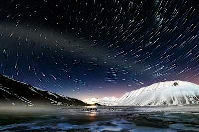 Busy Sky over snow covered mountains.