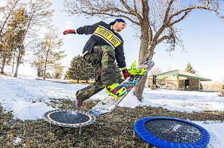 Le snowboarder Scott Stevens ride en snowboard sur deux trampolines.