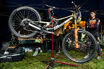 Jackson Goldstone stands next to his Santa Cruz v10 in the mechanics hut at Red Bull Hardline 2022.