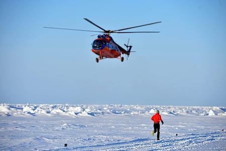 A runner passes a helicopter at the North Pole Marathon.