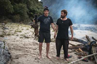 Rob Warner sostiene una comadreja junto a Josh James en el Buller District de Nueva Zelanda.