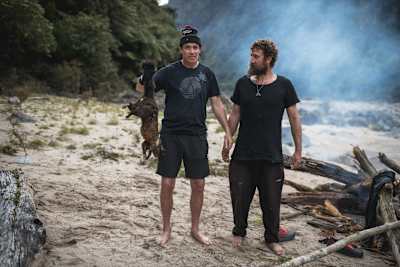 Rob Warner stands with Josh James and holds up a possum in the Buller District of New Zealand.