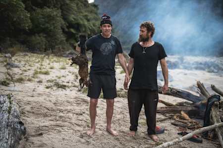 Rob Warner stands with Josh James and holds up a possum in the Buller District of New Zealand.