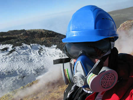 Grzegorz Gawlik stands at the top of a volcano in a face mask.