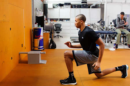 Een sporter traint in de gym de spieren in zijn onderlichaam door middel van lunges.