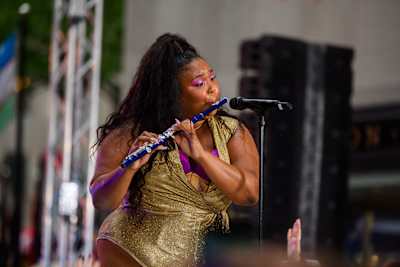 A photo of Lizzo player her flute live on stage in 2019.
